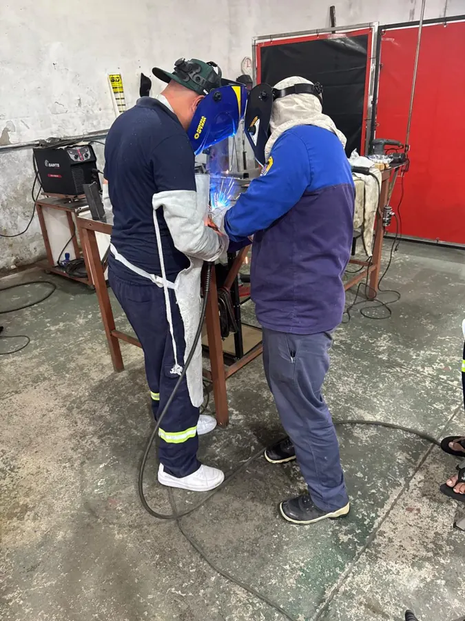 Instrutor orientando soldador em treinamento